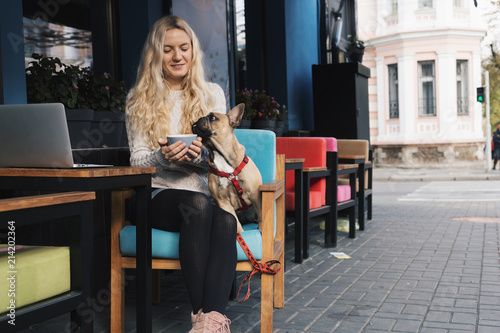 French bulldog relaxing in a cafe on blonde stylish woman's lap