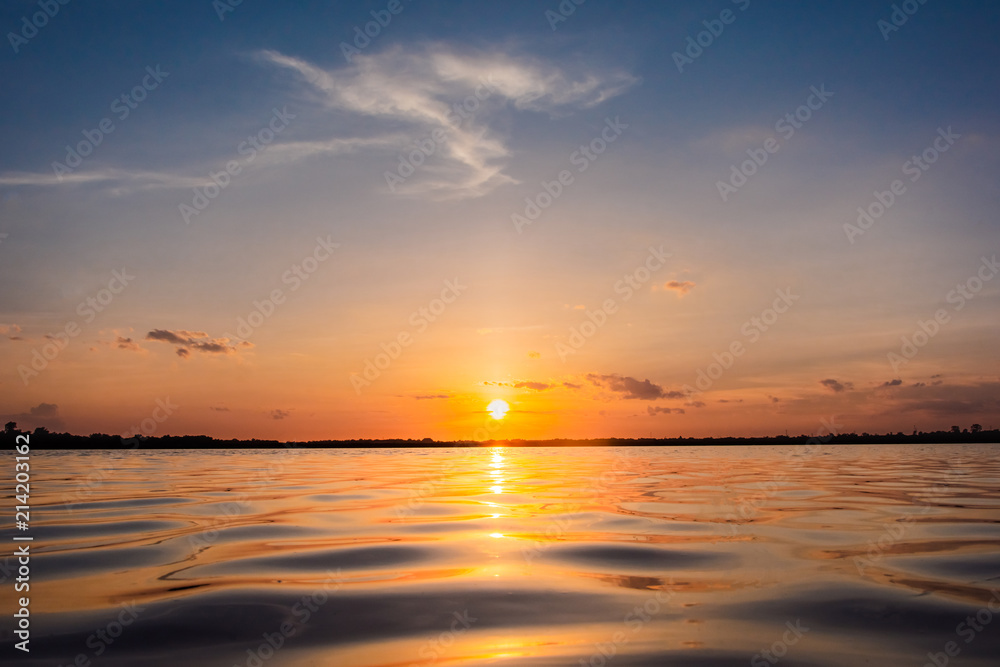 Fototapeta premium Sunset in the lake. beautiful sunset behind the clouds above the over lake landscape background. dramatic sky with cloud at sunset