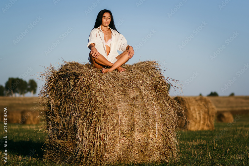 beautiful tanned brunette girl sitting in Lotus position on a haystack beautiful tanned brunette girl sitting in Lotus position on a haystack