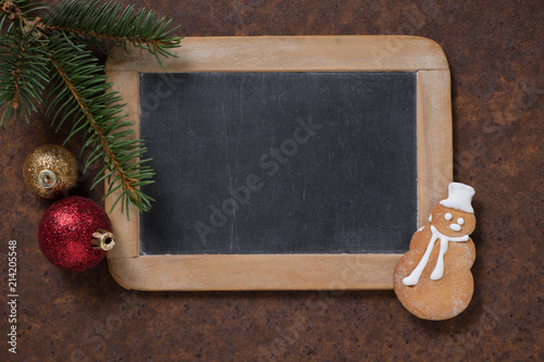 Christmas decoration. Blackboard and gingerbread Snowman, spruce twig and Christmas tree balls. Empty space for text.