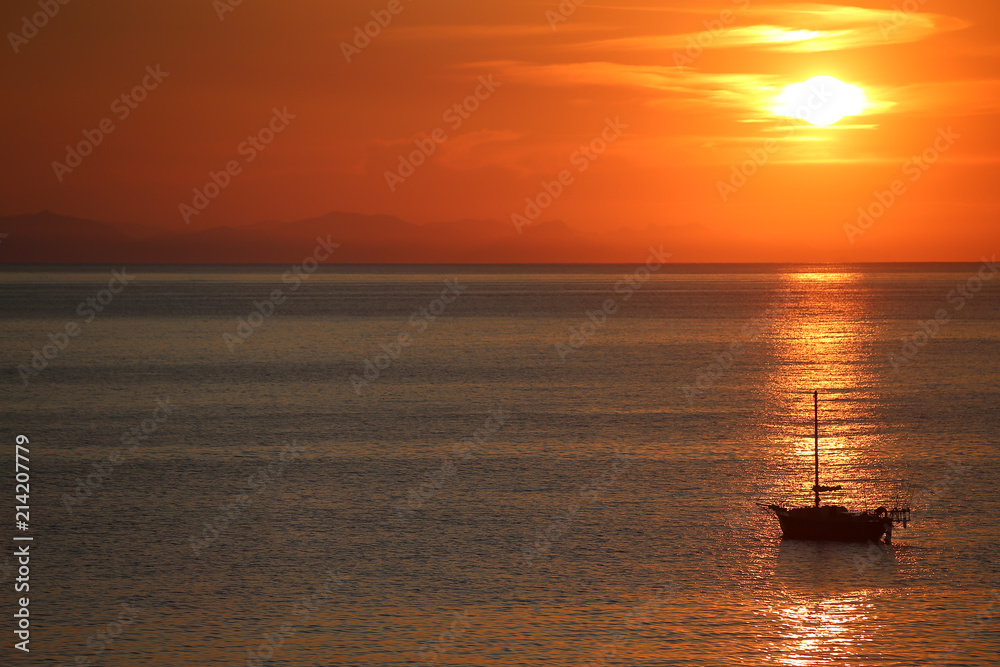 Ship in the sea on the sunrise near the coast