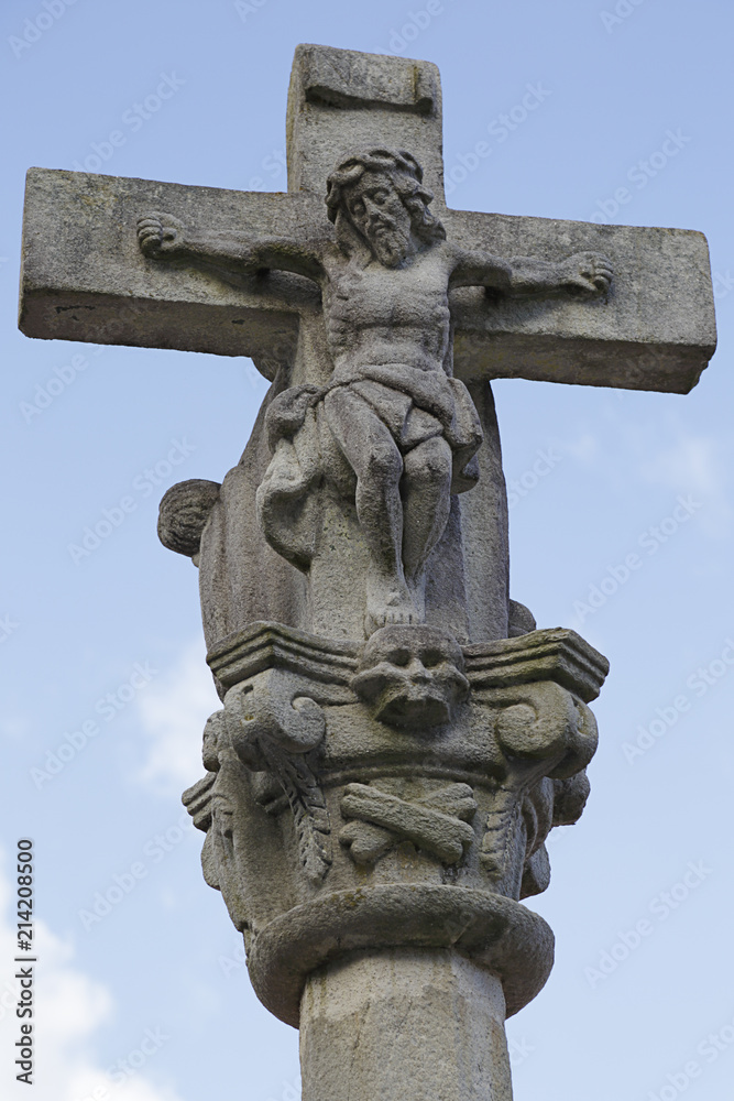 Ancient white stone crucifix with Jesus in blue sky
