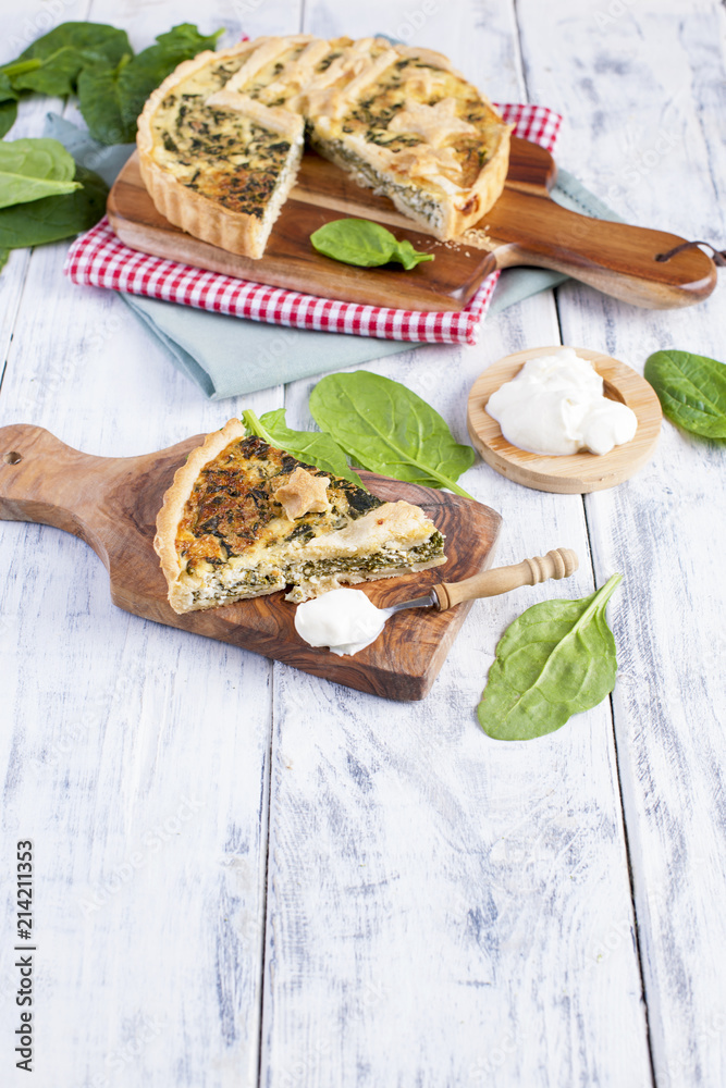 homemade pie with spinach and cheese, on a white wooden background. serving of pie. homemade pie with spinach and cheese, on a white wooden background. serving of pie.
