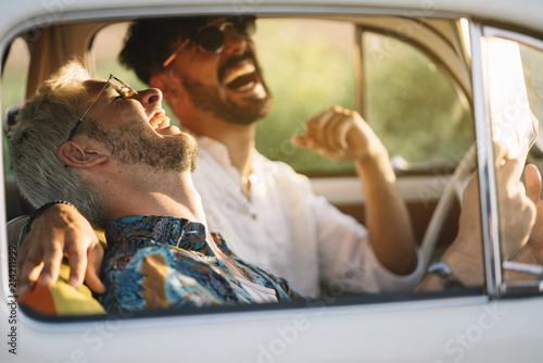 Cheerful gay couple reading map in car photo