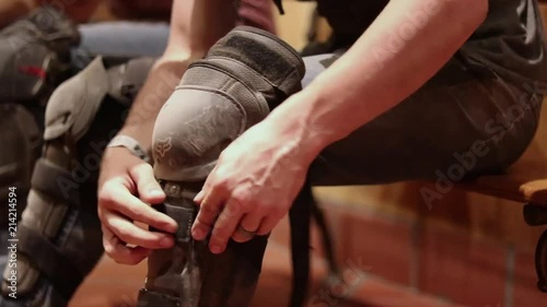 Man unstraps knee pads after a long day on the mountain. photo