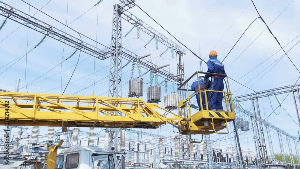 electricians lift up in hanging crane cradle to power lines electricians lift up in hanging crane cradle to power lines