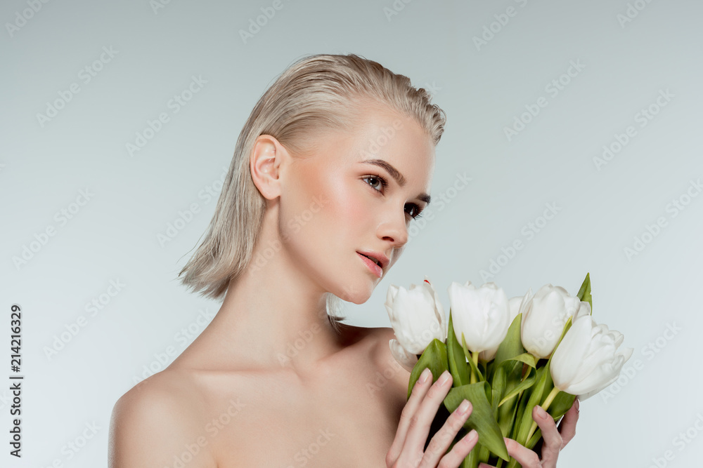 portrait of nude blonde girl posing with tulip flowers, isolated on grey portrait of nude blonde girl posing with tulip flowers, isolated on grey