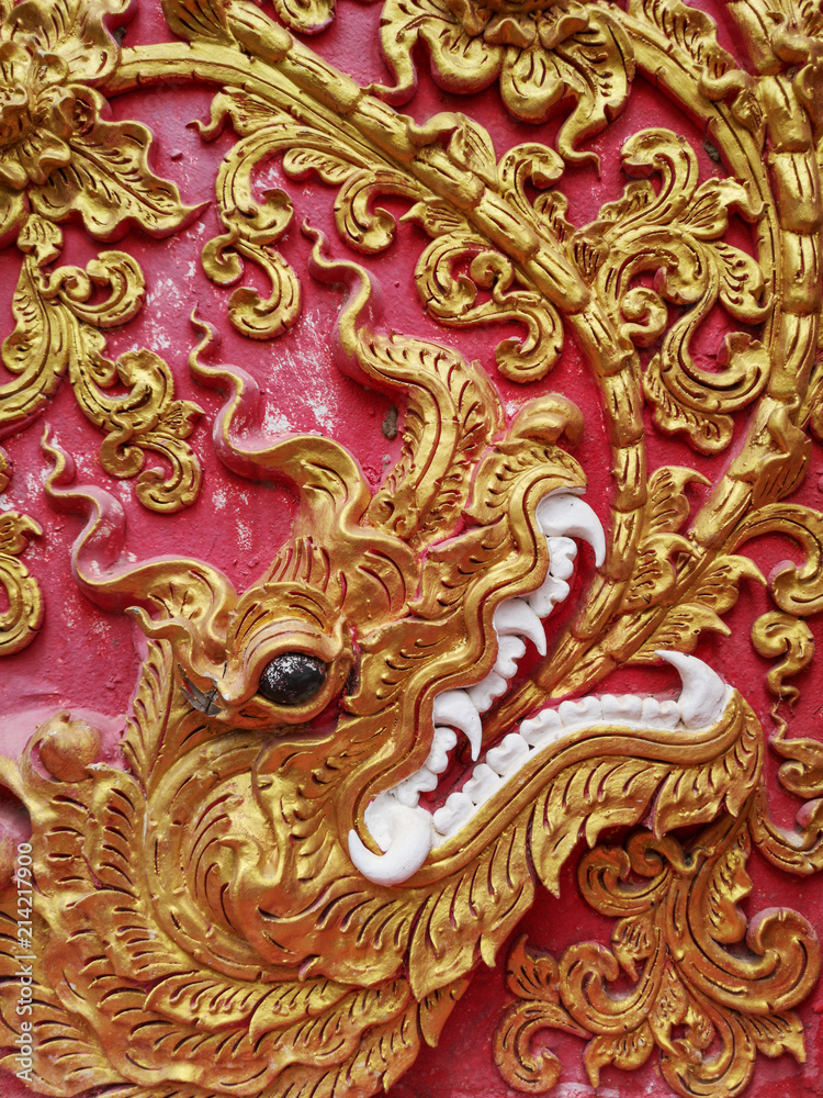Detail of Naga golden dragon head with big white teeth, ornamental buddhist pattern in buddhist temple in North Thailand