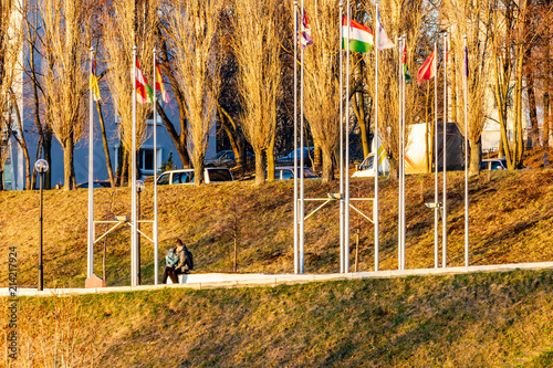 Guy and girl kissing under international flags on the hillside at sunset. photo