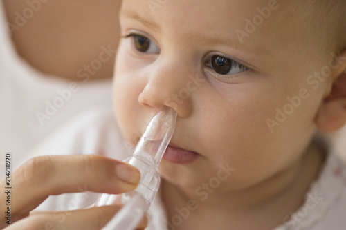 mother cleaning babies nose. nasal aspiration connected to vaccum cleaner photo