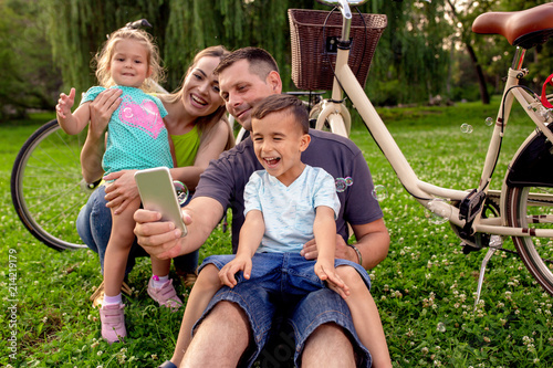 Happy family smiling while taking self - portrait in park. photo