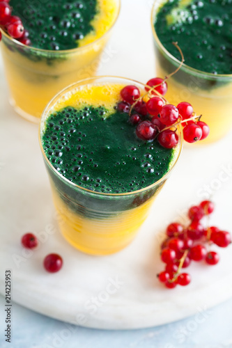 two colored fresh smoothies in glasses with fresh berries. orange banana juice with spirulina powder. detox breakfast. healthy eating photo