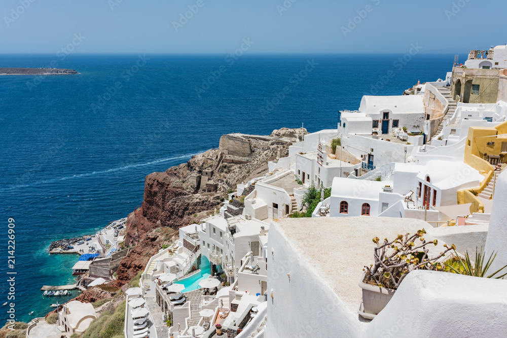 Fototapeta premium Tiny little white houses, hotels and small churches in the Oia village at Santorini, Greece.