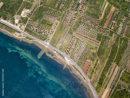 Vista aerea di una strada che costeggia la costa croata e attraversa campi agricoli, con piantagioni e campi coltivati. Strada che costeggia il mare. Tratto di costa photo