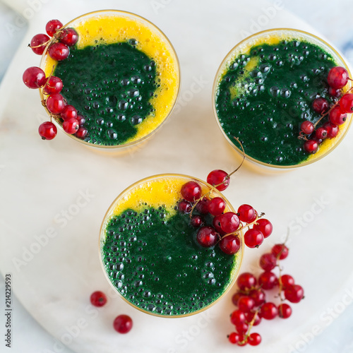 two colored fresh smoothies in glasses with fresh berries. orange banana juice with spirulina powder. detox breakfast. healthy eating photo