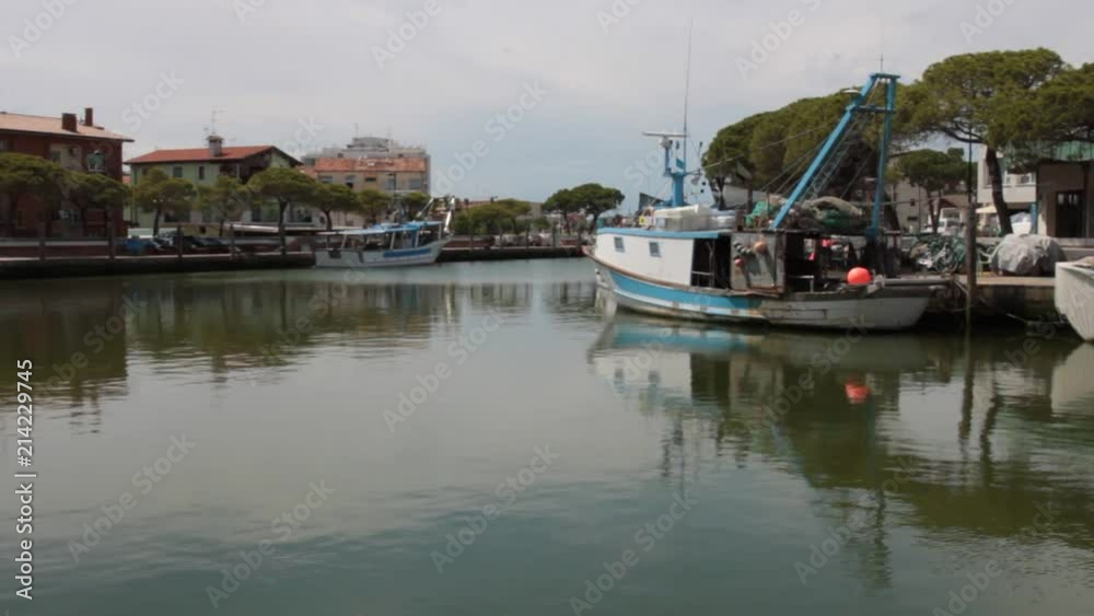View of the canal and the port of Caorle with moored fishing boats View of the canal and the port of Caorle with moored fishing boats