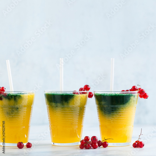 two colored fresh smoothies in glasses with fresh berries. orange banana juice with spirulina powder. detox breakfast. healthy eating photo