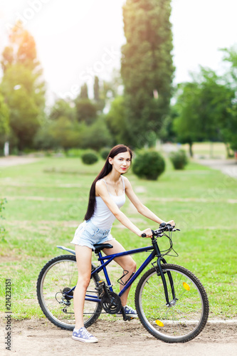 Teen girl with bicycle in a park.