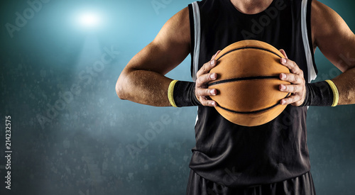 Basketball ball in a male hands, player in black with orange sport ball