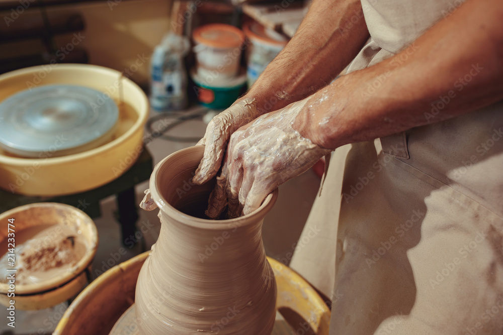 Creating a jar or vase of white clay close-up. Master crock. Man hands making clay jug macro.