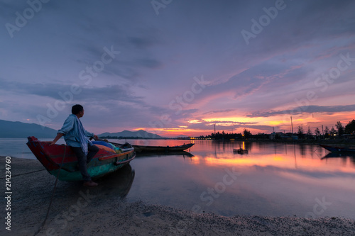 Sunset on Lap An lagoon and Lang Co bay with colorful clouds and a man looking away. Lang Co Bay is one of the most famous and beautiful bays of the world. HUE - VIETNAM date 29/04/2018