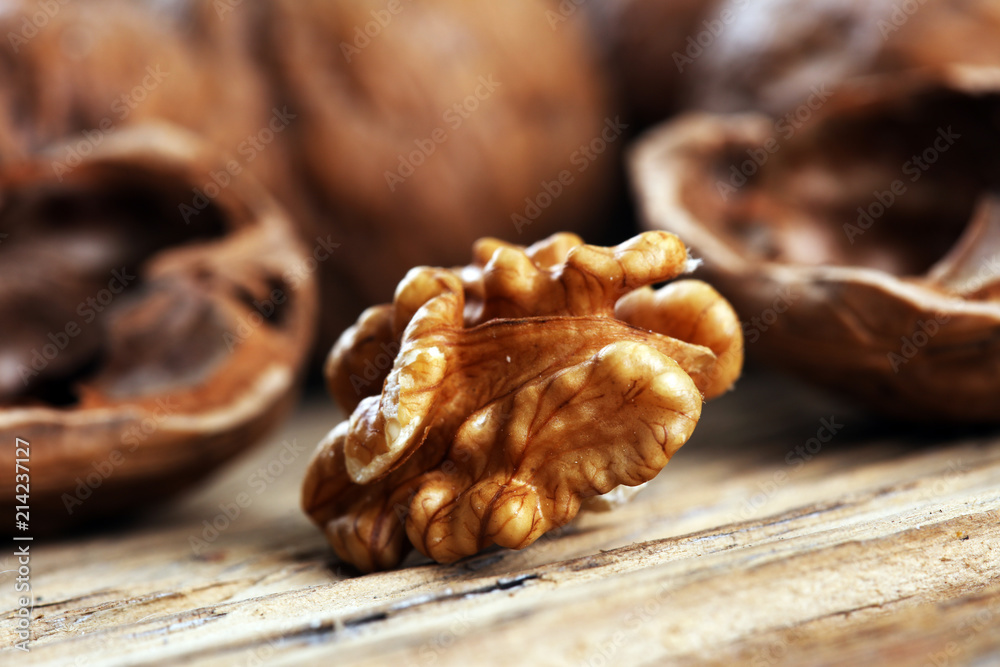 Fototapeta premium Walnut kernels and whole walnuts on rustic old table.