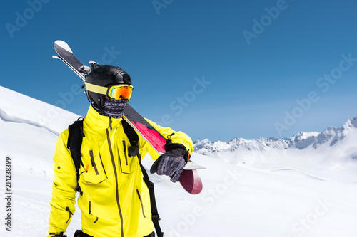 Skier standing on a slope. Man in a light suit, the helmet and mask in skiing is to ski. In the background snow-capped mountains , skiers . Caucasus Mountains, Elbrus, Russia