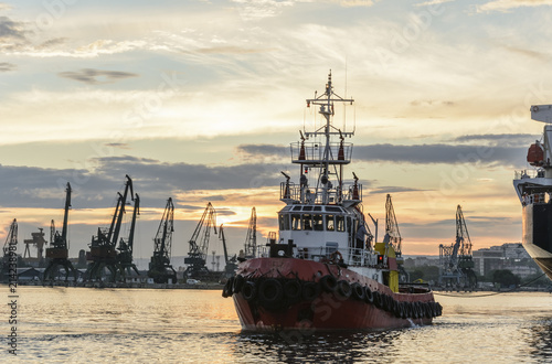Tug boat entering the harbor with big cargo boat.