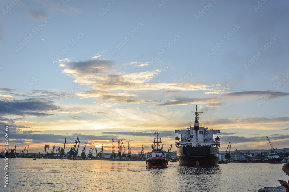 Tug boat entering the harbor with big cargo boat.