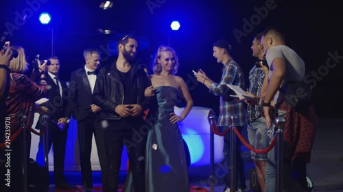 Artists arriving on celebrity event and standing on red carpet while interacting with fans and photographers