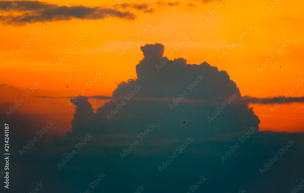 Dark, blue clouds against the backdrop of a bright, orange sunset. Beautiful and ominous at the same time
