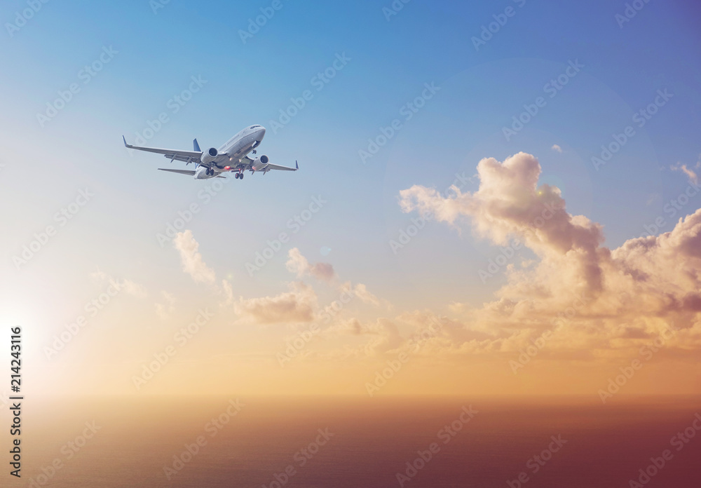 Naklejka premium airplane flying above ocean with sunset sky background - travel concept 