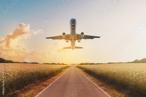 airplane flying above empty road in rural landscape - travel concept
