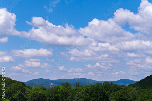 green tops of trees and mountains under the boundless heavenly ocean