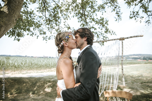 Hochzeitspaar küsst sich bei Outdoor Boho Hochzeit photo