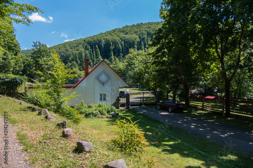 beautiful house in a mountainous area with a gate facing in the shade of a car tree