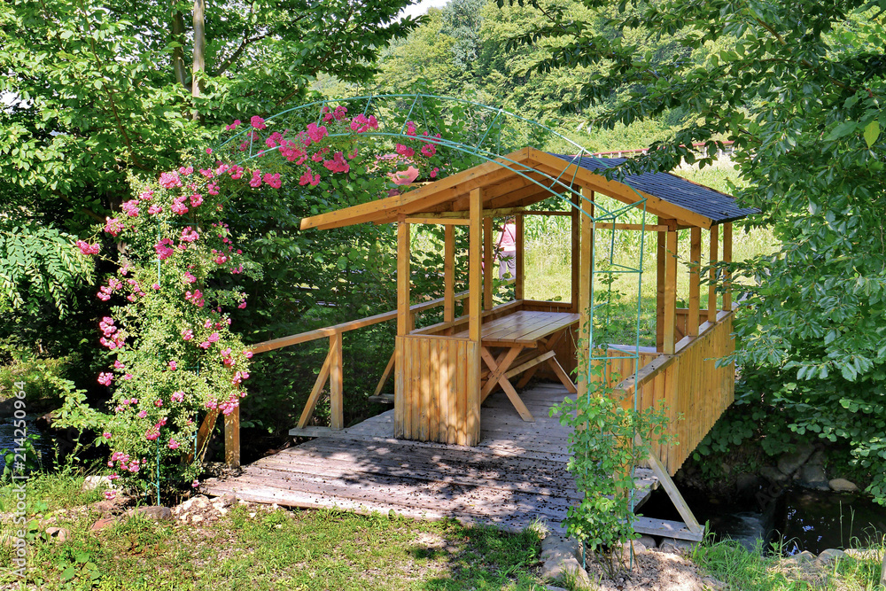 A beautiful wooden gazebo in the garden, for cozy summer farmhouses in the evening for a bottle of beer or a glass of wine A beautiful wooden gazebo in the garden, for cozy summer farmhouses in the evening for a bottle of beer or a glass of wine