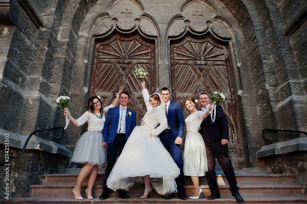 Wedding couple and groomsmen with bridesmaids posing by the old door in an old town.