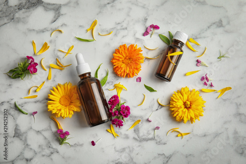 Flat lay composition with essential oils and flowers on marble background