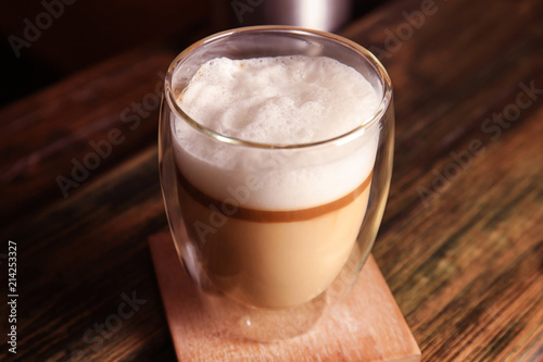 Glass with delicious latte on wooden table