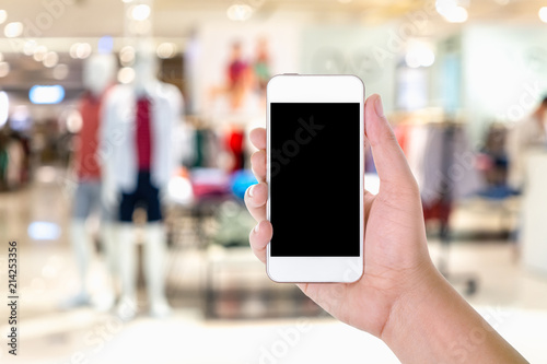 Man hand holding and using blank screen mobile smart phone with blurred background fashion shop in shopping mall