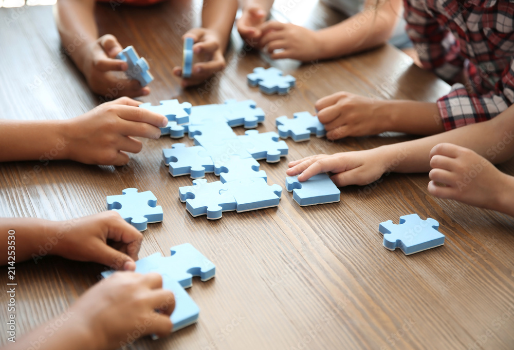 Little children playing with puzzle at table, focus on hands. Unity concept Little children playing with puzzle at table, focus on hands. Unity concept
