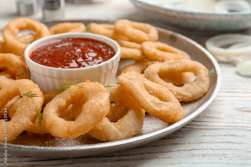 Fried onion rings served with sauce on plate, closeup Fried onion rings served with sauce on plate, closeup