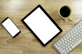blank screen smartphones and tablet PC on the wooden desktop with computer keyboard and a cup of coffee in composition with copy space for your text