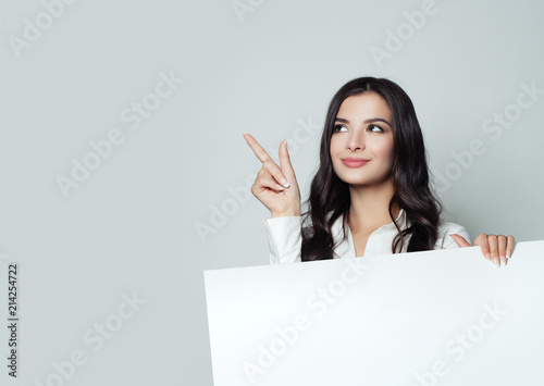 Happy young businesswoman pointing up and showing signboard with blank copy space area for tagline, advertisiment or text message on white background. Success in business, advertising marketing  photo