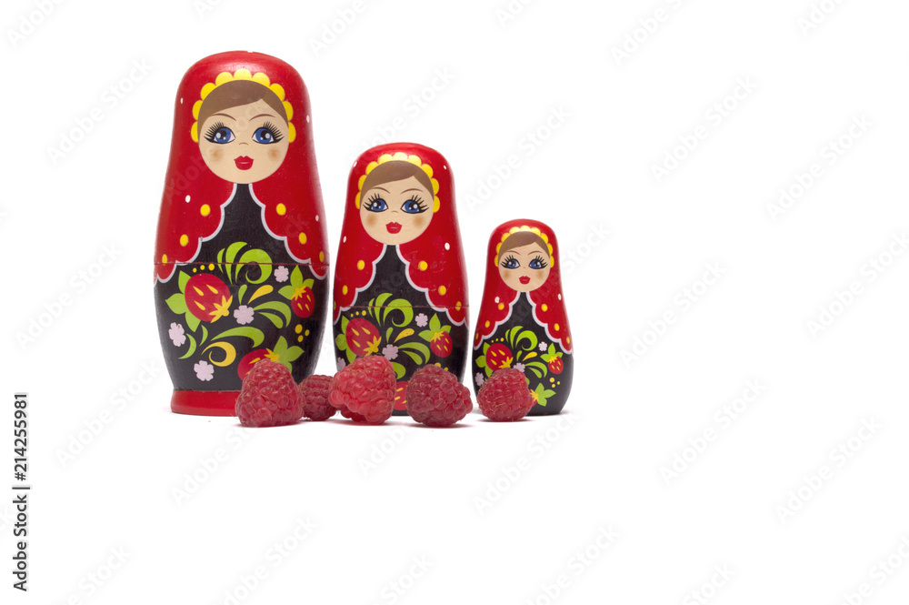 Traditional wooden doll's Matreshka Babushka with raspberries isolated on a white background