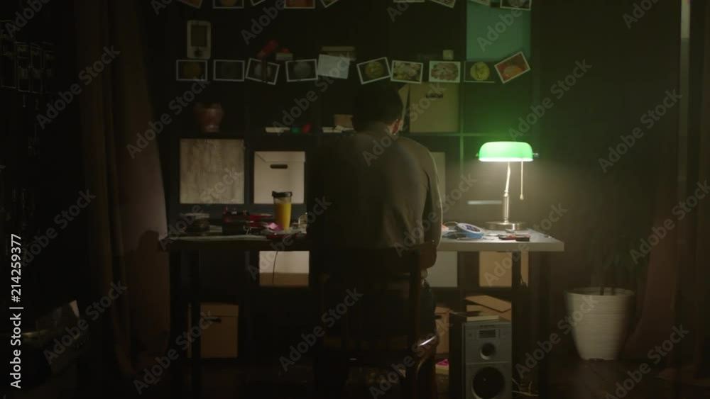 Tired young man working with laptop at home in evening. Stock. Sad lonely man sitting at the table at home. The concept of loneliness