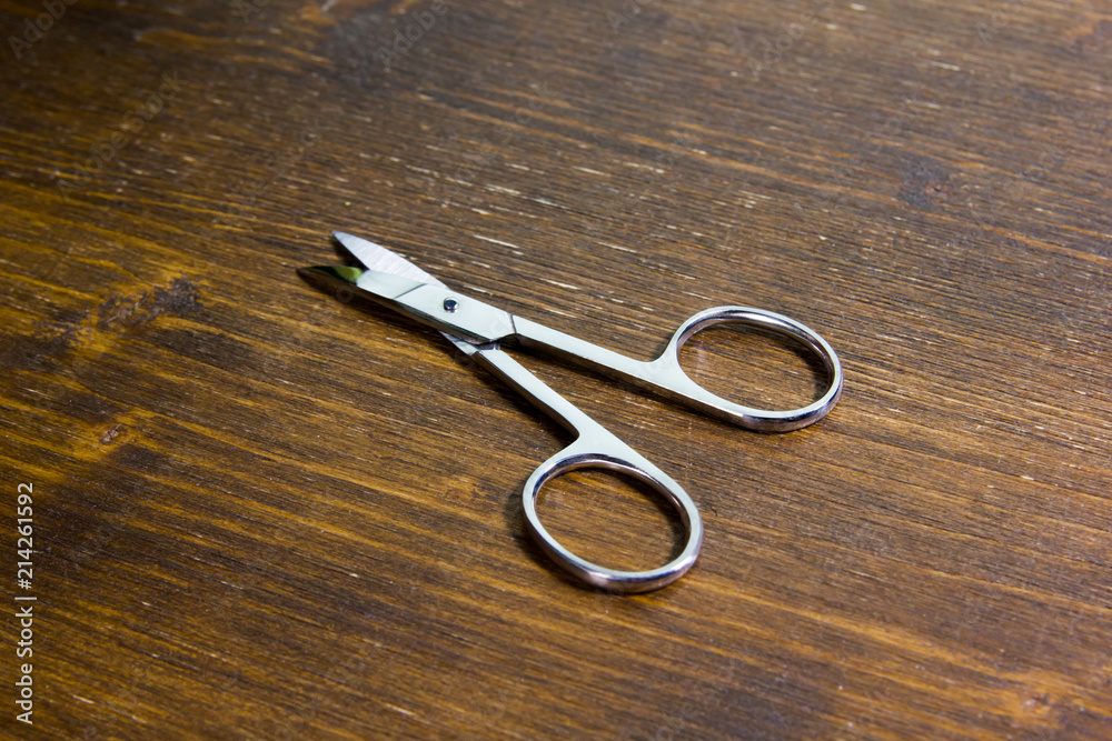 Manicure scissors on a wooden table viewed from close up Manicure scissors on a wooden table viewed from close up