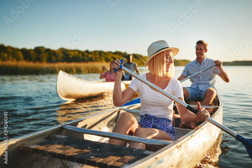 Laughing young woman canoeing on a lake with friends photo