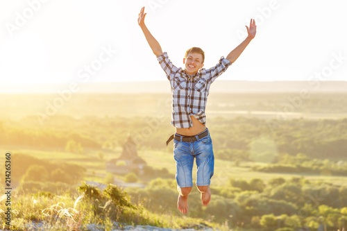 happy guy jumping to the top on the background of nature and sun concept of success and happiness